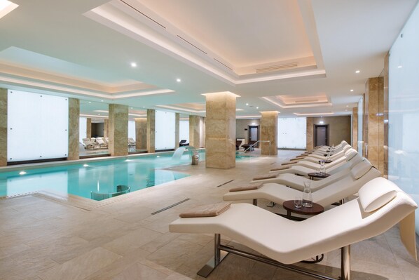 Un área de piscina interior moderna con sillones de descanso y vistas despejadas a la piscina.