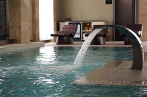 A pool with a water feature, lounge chairs, and a reception area. - Grand Hotel Kempinski Riga (Riga)