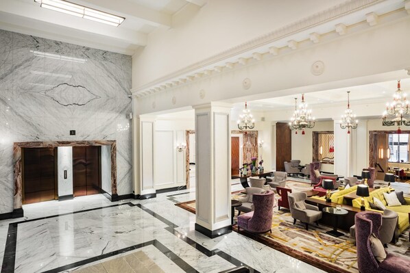 A spacious lobby with marble flooring, a reception desk, multiple seating areas, and decorative chandeliers. - Grand Hotel Kempinski Riga (Riga)