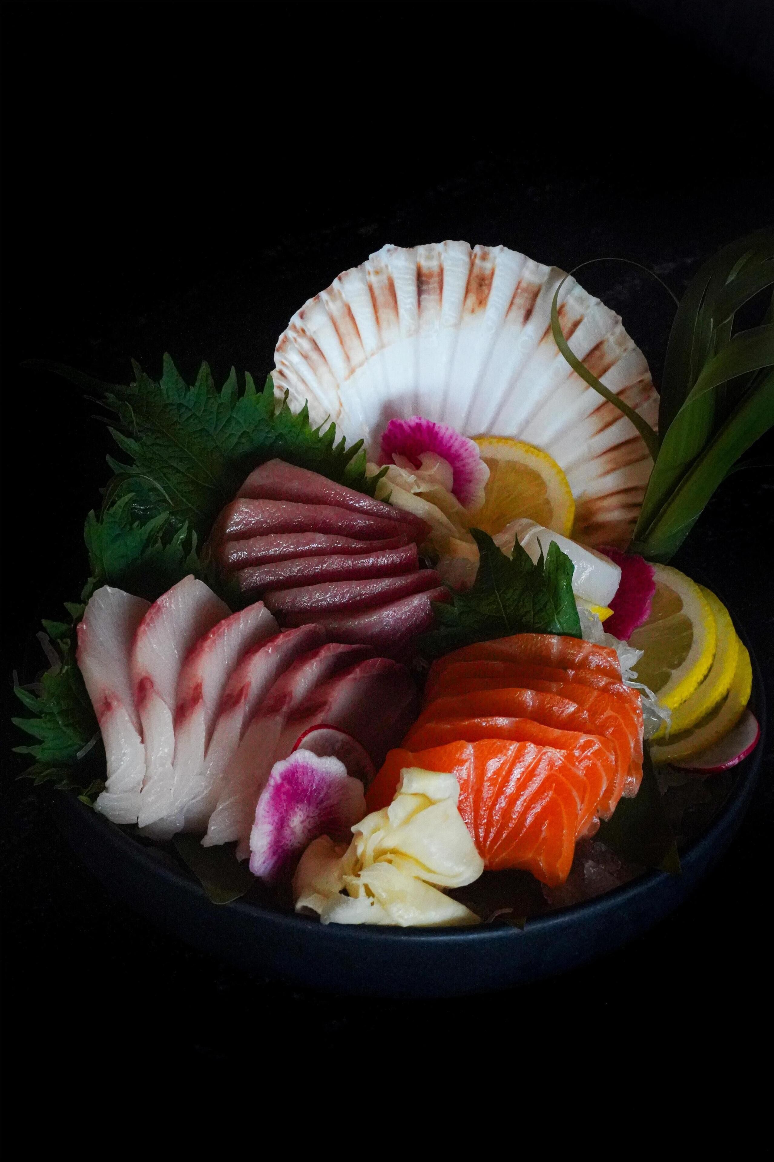 A bowl of sashimi with various types of fish and garnishes.