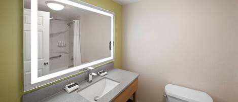 A bathroom with a large mirror, a sink, and a toilet.