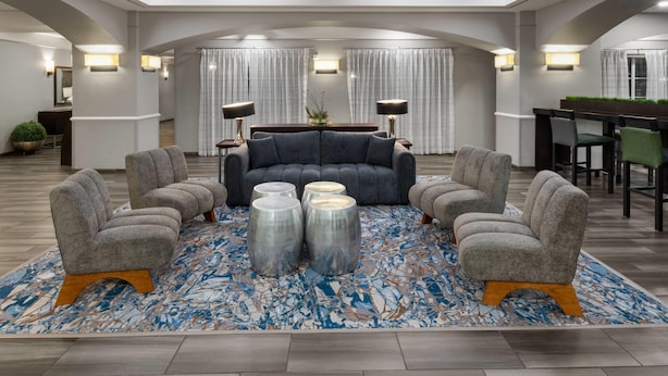 A spacious living area with a dark blue sofa, four grey armchairs, and three metallic coffee tables.