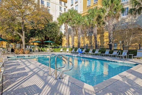 Una piscina al aire libre, sillones reclinables de piscina