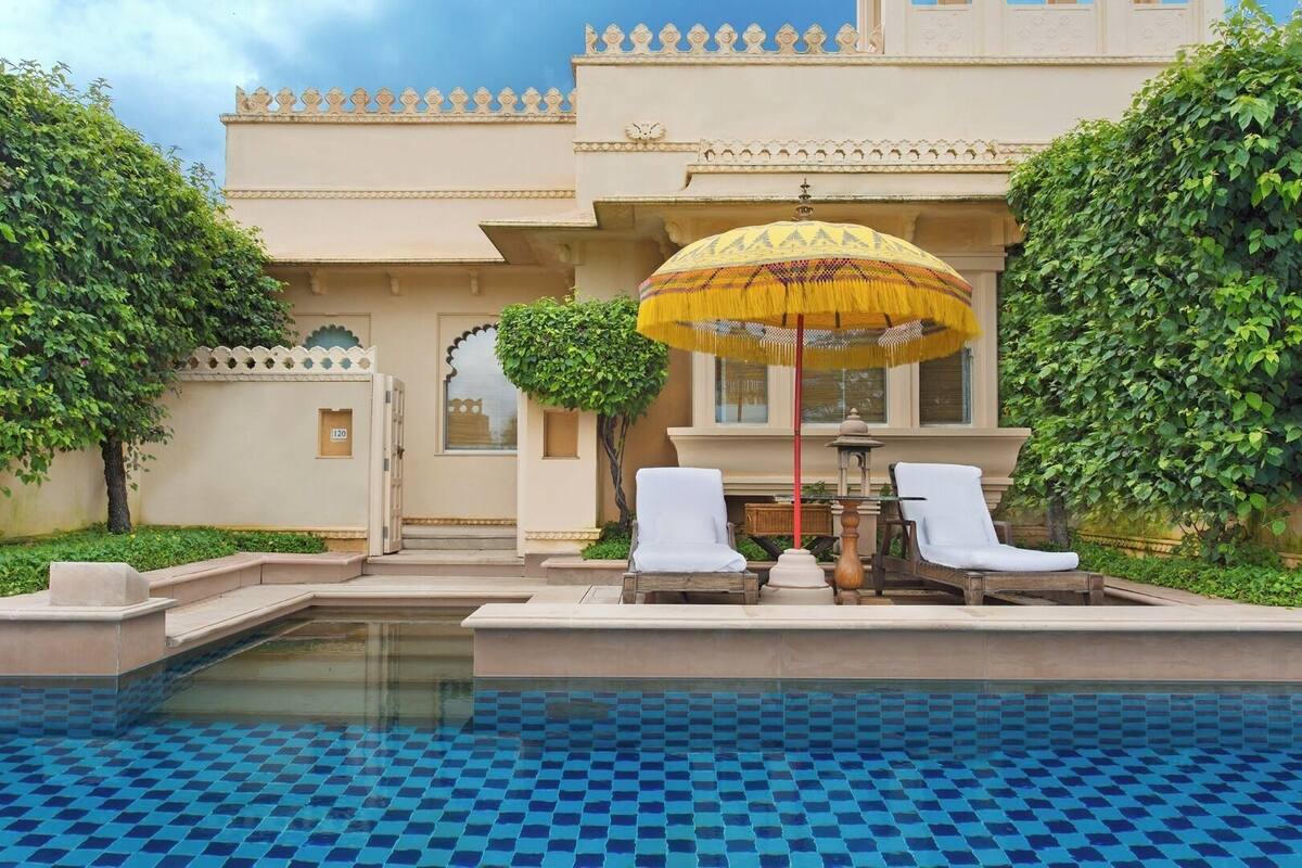 A pool area with two white lounge chairs and a table under a yellow umbrella.