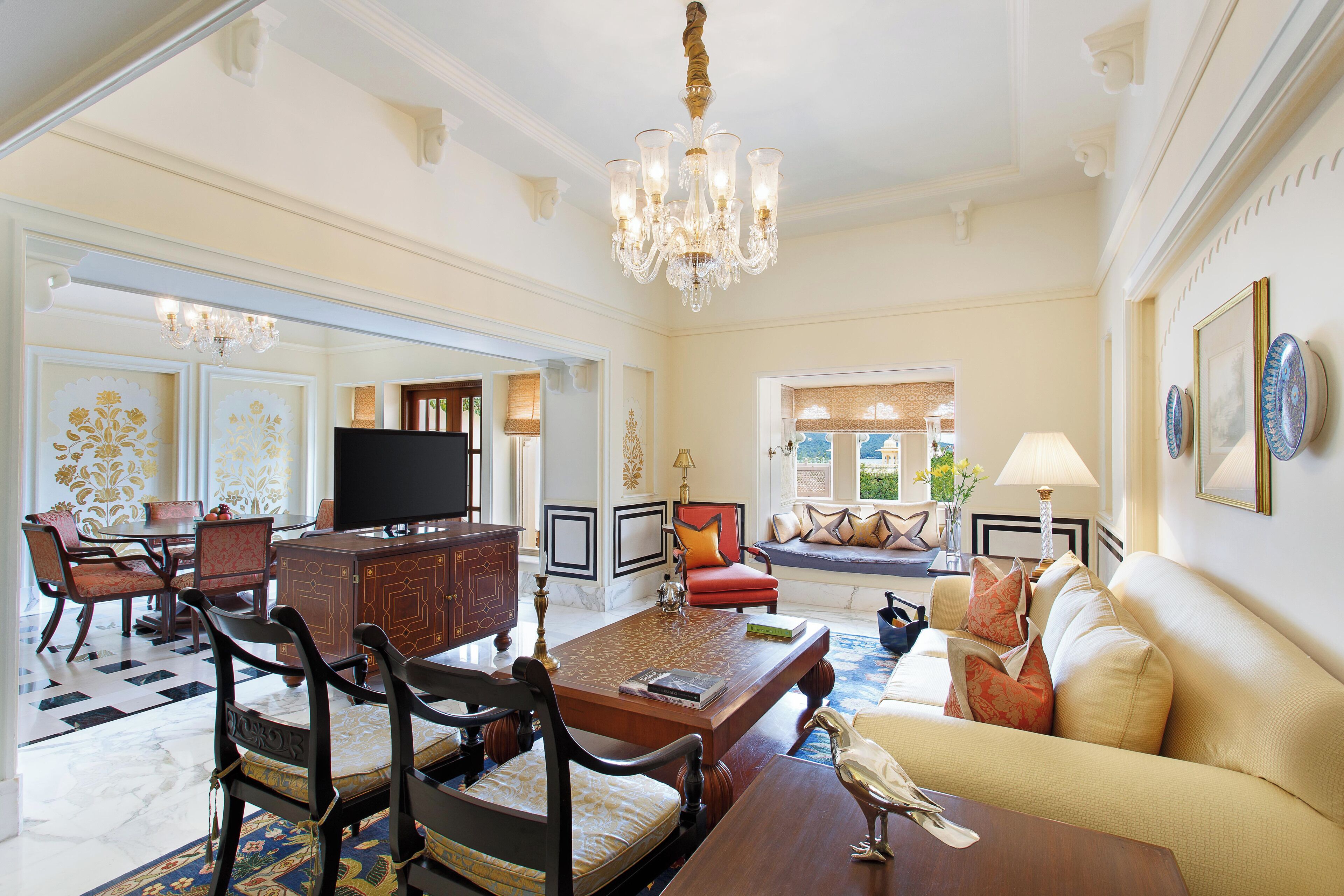 A spacious living room with a large wooden coffee table, a television, and a chandelier.