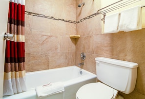 A bathroom with a bathtub, toilet, and towel rack. - Red Roof Inn & Suites Greenwood, SC (Greenwood)