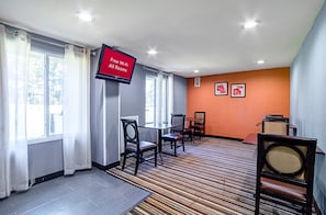 A hotel room with a TV displaying "Free Wi-Fi All Rooms," a striped carpet, and a view of trees through the window. - Red Roof Inn & Suites Greenwood, SC (Greenwood)