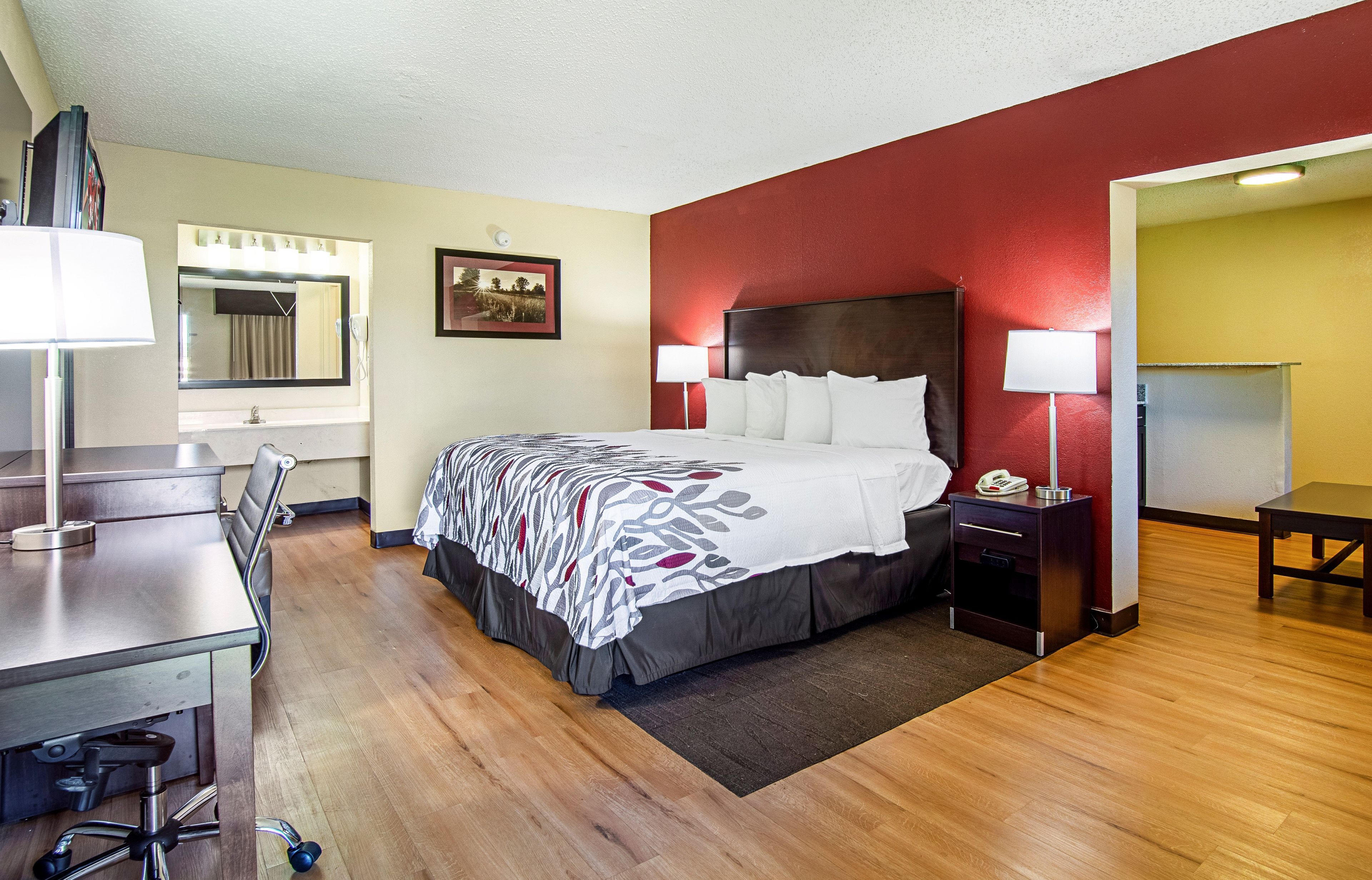 A hotel room with a bed, bedside tables, a desk, and a chair.