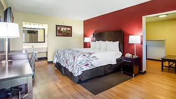 A hotel room with a bed, bedside tables, a desk, and a chair.