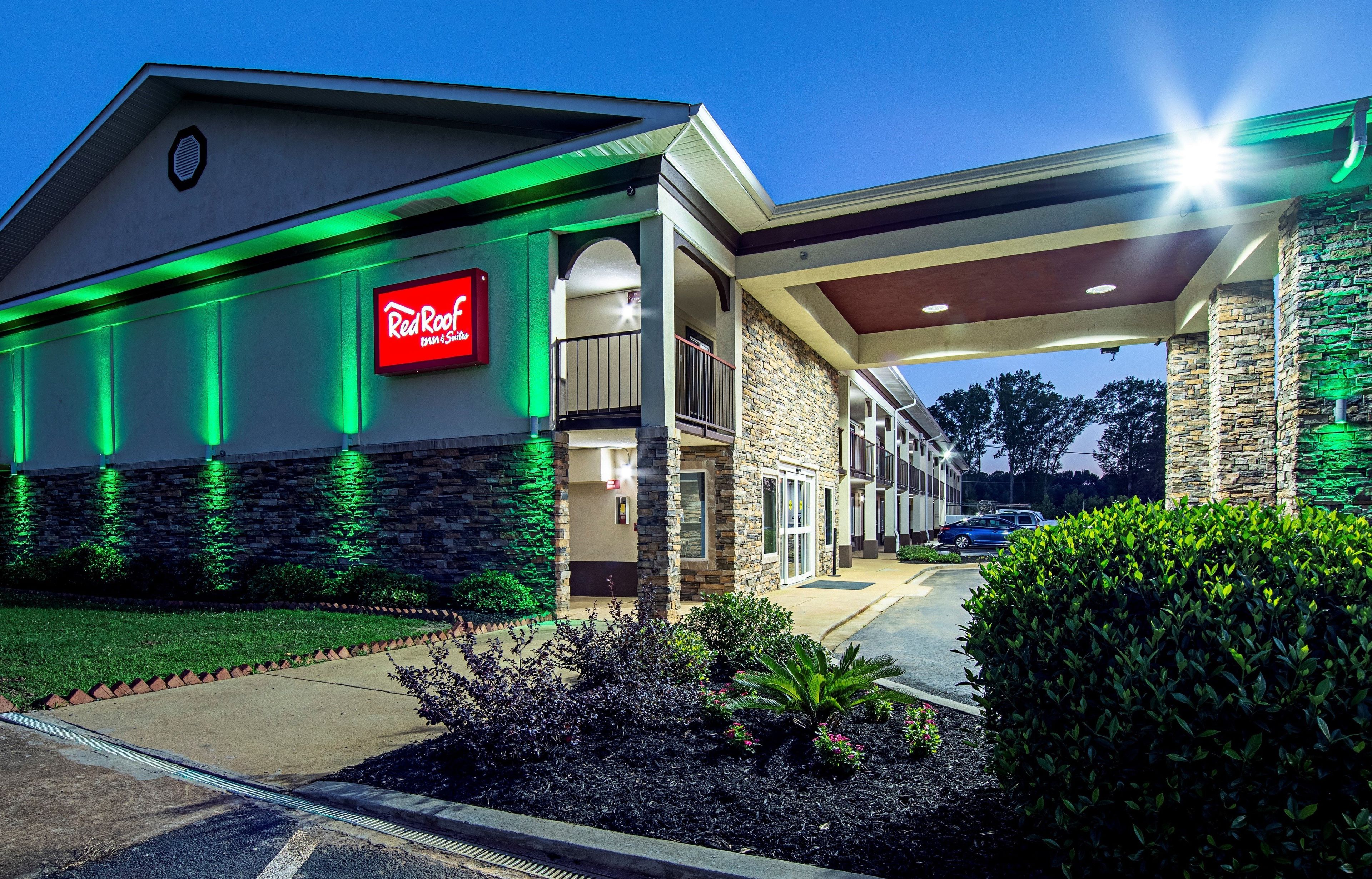 A Red Roof Inn & Suites with a stone facade, a covered entrance, and a parking lot.
