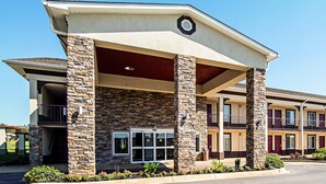 A hotel with a stone facade, multiple balconies, and a covered entrance. - Red Roof Inn & Suites Greenwood, SC (Greenwood)