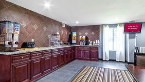 Een moderne keuken met een marmeren aanrechtblad, inbouwkeukens, een koffieapparaat en een flatscreen-tv waarop staat: "Free Wi-Fi All Rooms".