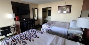 A hotel room with two beds, a TV, a desk with a lamp, a dresser, and a mirror. - Red Roof Inn & Suites Greenwood, SC (Greenwood)
