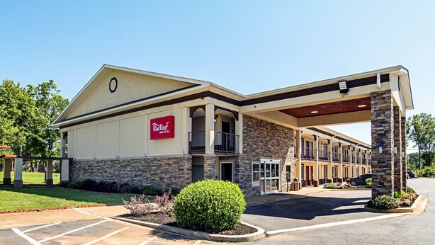A Red Roof Inn & Suites with a stone facade, a covered parking area, and a landscaped entrance. - Red Roof Inn & Suites Greenwood, SC (Greenwood)