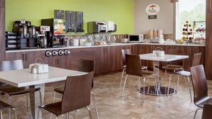 Una cucina moderna con una parete verde, macchine da caffè, un forno a microonde e un buffet per la colazione.