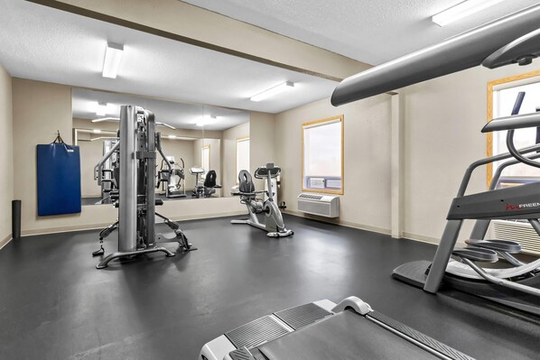 A gym with various exercise equipment, including a treadmill, weight machines, and a punching bag. - Super 8 by Wyndham Prince Albert (Prince Albert)