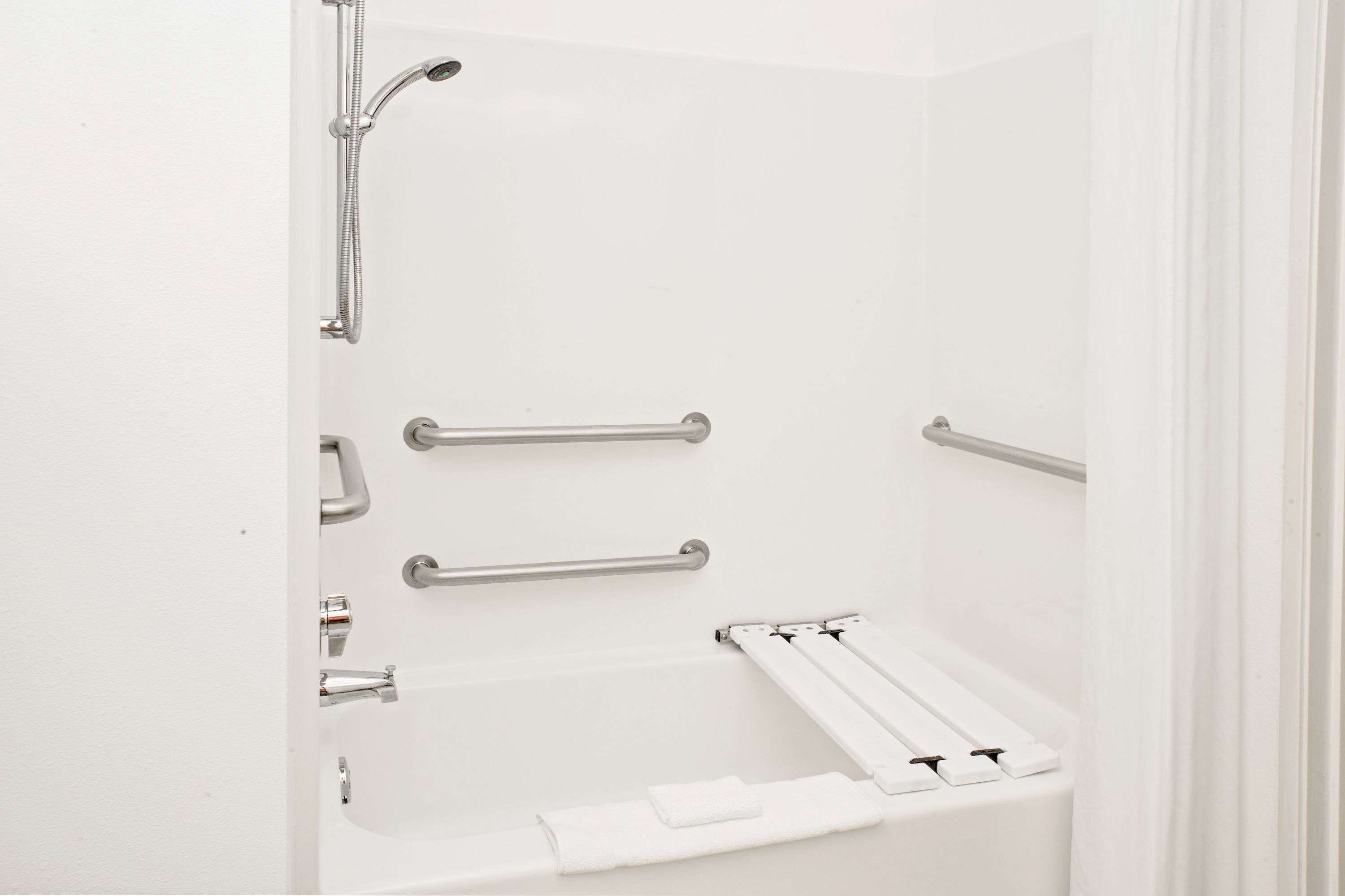 A white bathtub with grab bars and a showerhead.