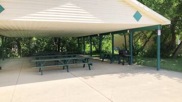 A covered picnic area with benches and a grill.