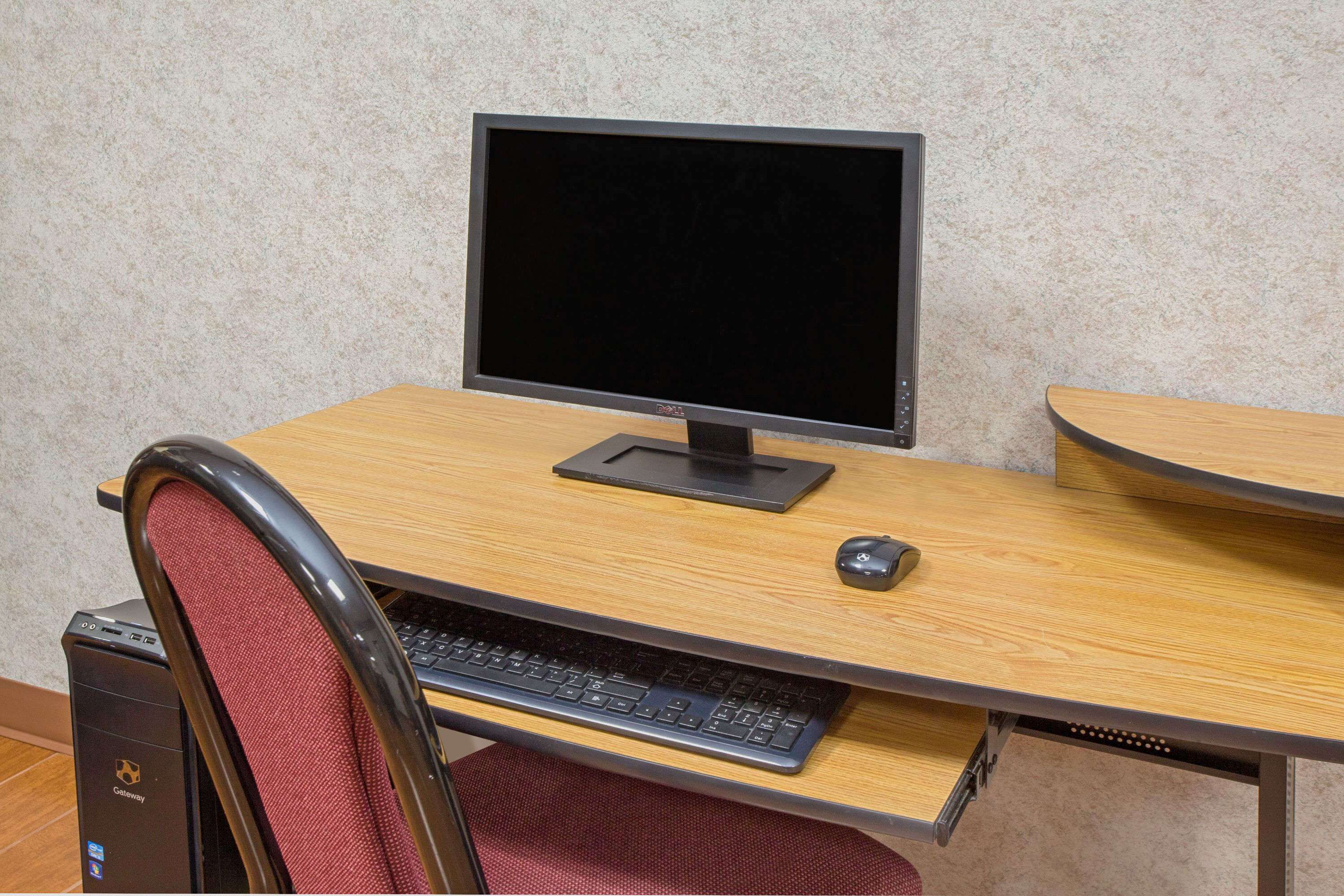 A computer desk with a monitor, keyboard, and mouse.