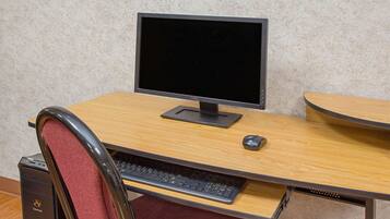 A computer desk with a monitor, keyboard, and mouse.