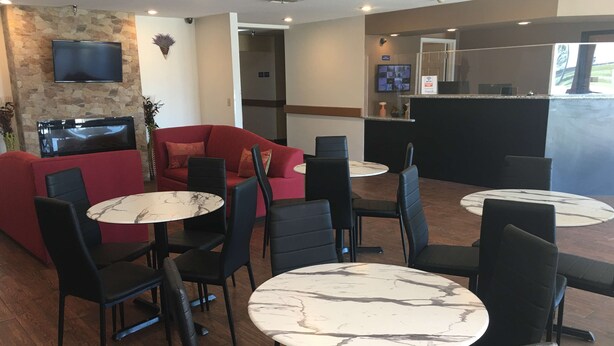 Moderni sisätila, jossa on punainen sohva, mustat tuolit ja marmoripintaiset pöydät.