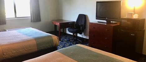 A hotel room with two beds, a desk, a chair, a television, and a dresser.