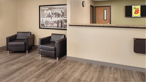 A reception area with two black leather chairs, a framed welcome sign, a clock, and a Super 8 sign on the wall. - Super 8 by Wyndham Sioux Falls (Sioux Falls)