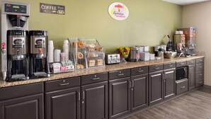 A coffee shop counter with espresso machines, a coffee grinder, and a display of pastries and coffee cups. - Super 8 by Wyndham Sioux Falls (Sioux Falls)