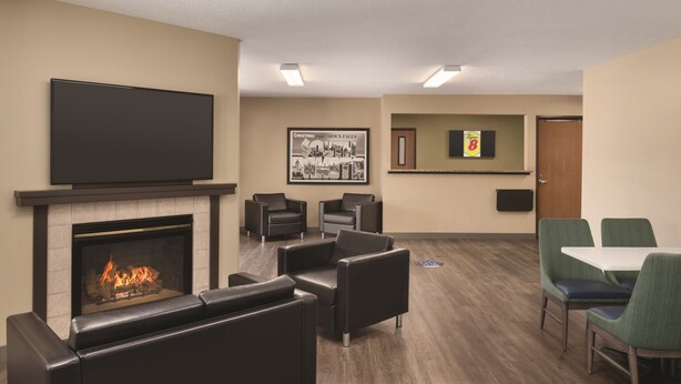 A modern lounge area with a fireplace, comfortable seating, a flat-screen TV, and a framed welcome sign. - Super 8 by Wyndham Sioux Falls (Sioux Falls)