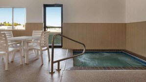 A spa area with a hot tub, a table with chairs, and a view through a door. - Super 8 by Wyndham Sioux Falls (Sioux Falls)