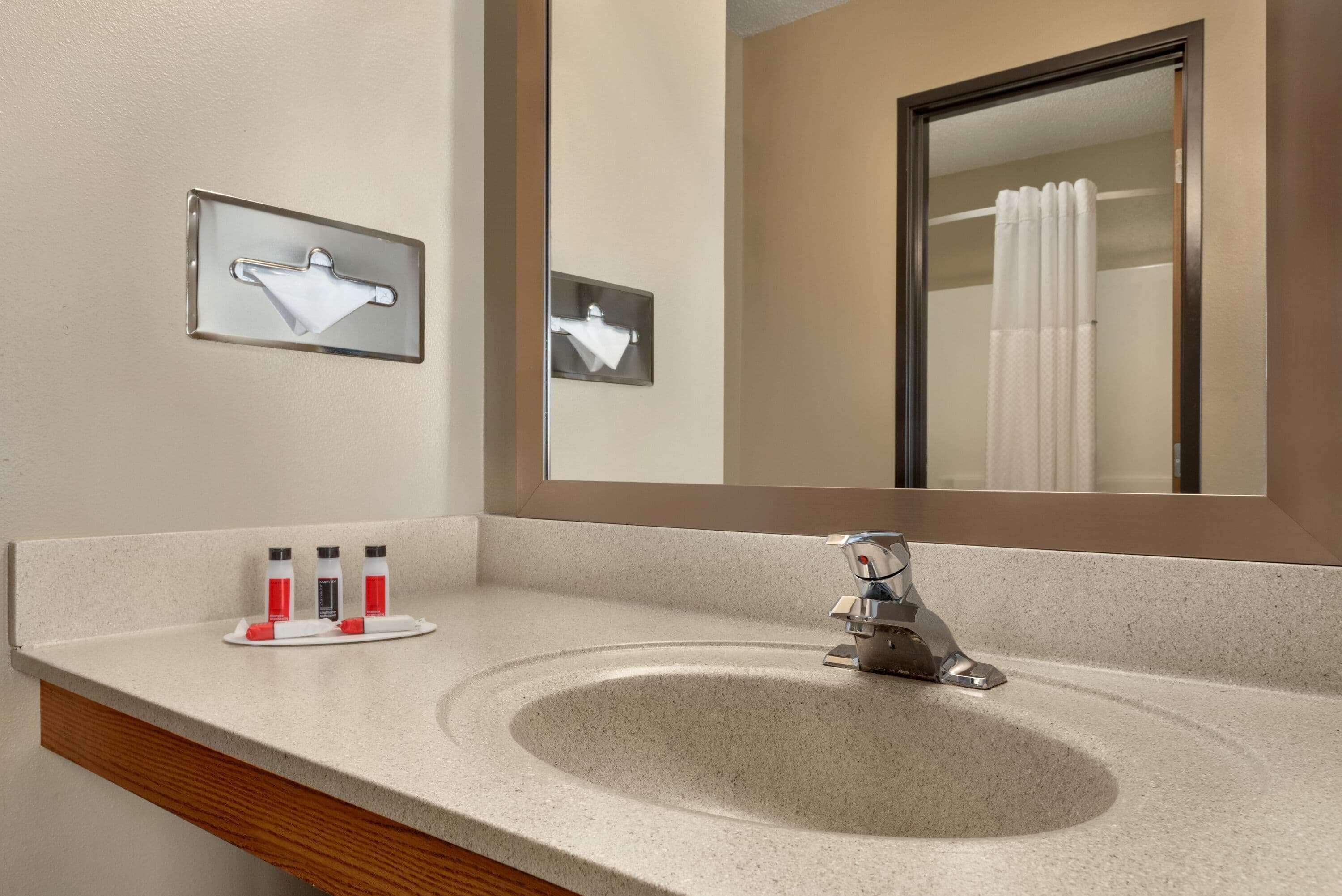 A bathroom with a sink, mirror, towel rack, and toiletries.
