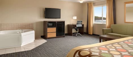 Habitación de hotel con cama, escritorio, silla, televisión, microondas, refrigerador minibar, bañera y ventana con cortinas.
