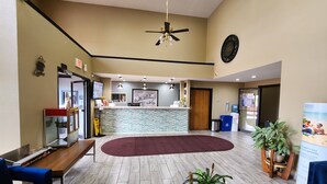 Un hall de hotel con mostrador de recepción, zona de estar y ventilador de techo.