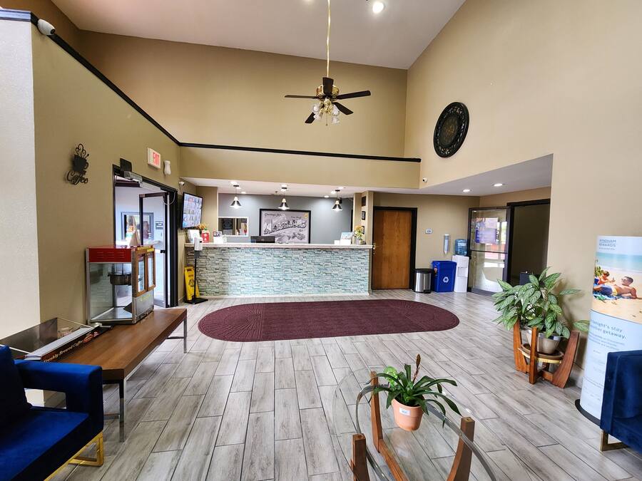 A hotel lobby with a reception desk, seating area, and a ceiling fan.