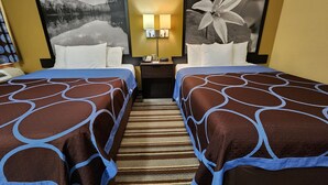 Habitación de hotel con dos camas, una mesita de noche con lámpara y dos cuadros grandes en las paredes.