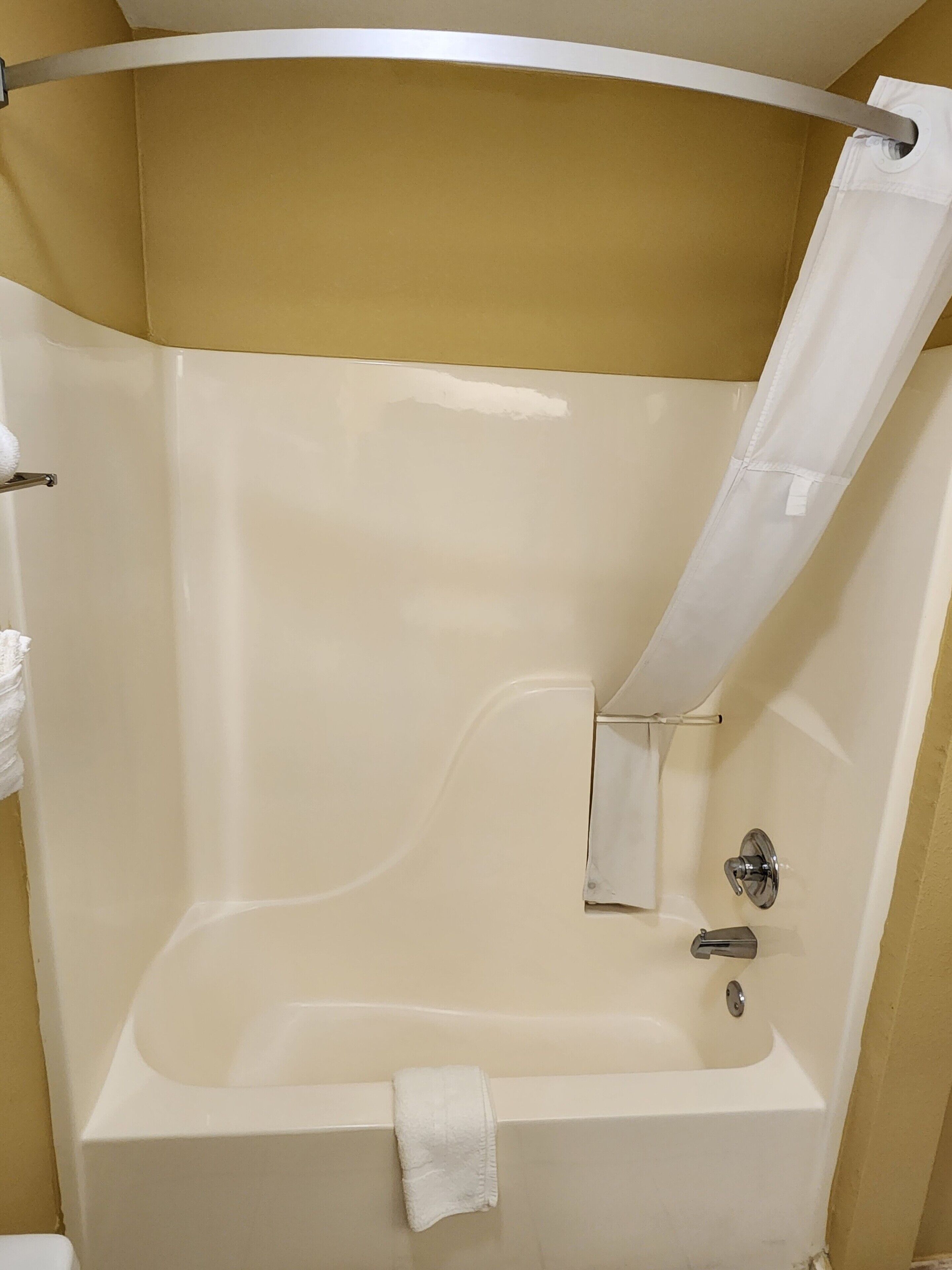 Eine Badewanne mit Duschvorhang, Handtuchhalter und Wasserhahn.