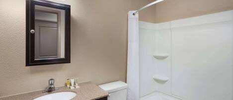 A bathroom with a sink, mirror, and shower.