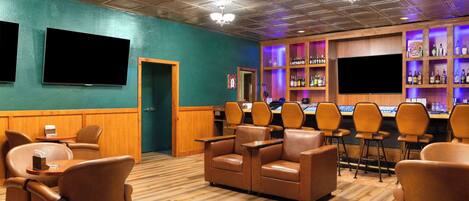 A bar area with leather chairs, a counter, and shelves of liquor bottles.