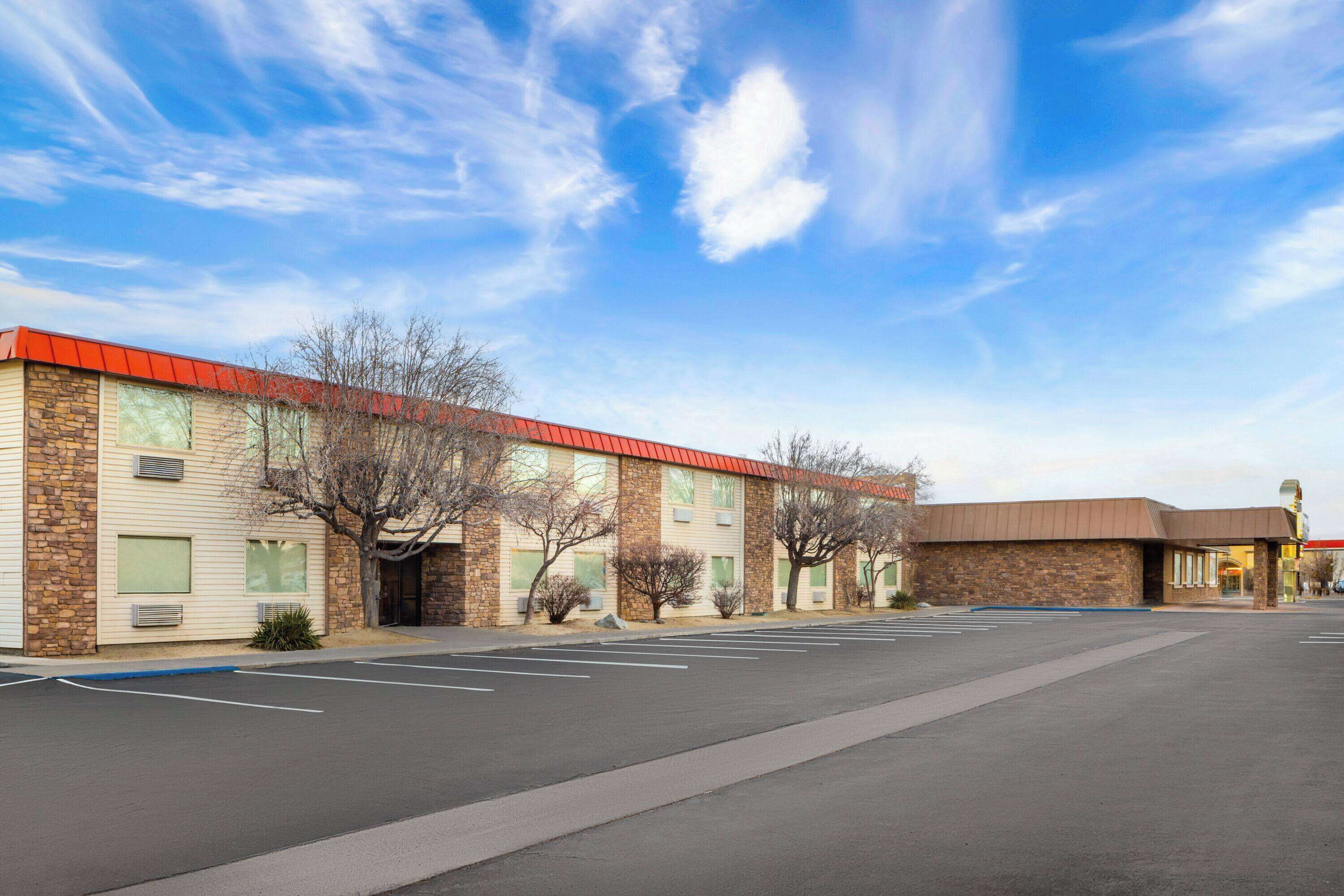 A building with a red roof and stone facade, a parking lot, and leafless trees.
