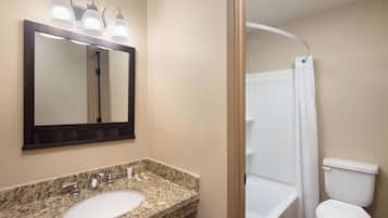 A bathroom with a granite countertop sink, a mirror, and a shower curtain.