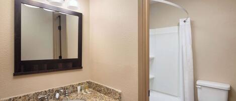 A bathroom with a granite countertop sink, a mirror, and a shower curtain.
