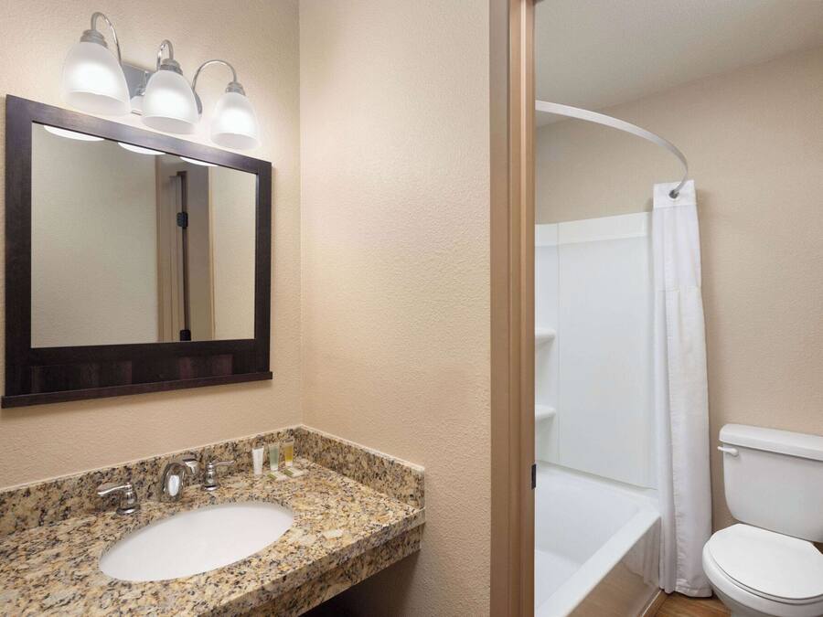 A bathroom with a granite countertop sink, a mirror, and a shower curtain.