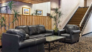 A lobby with a leather sofa, a small table, and a staircase. - Super 8 by Wyndham Fallon (Fallon)