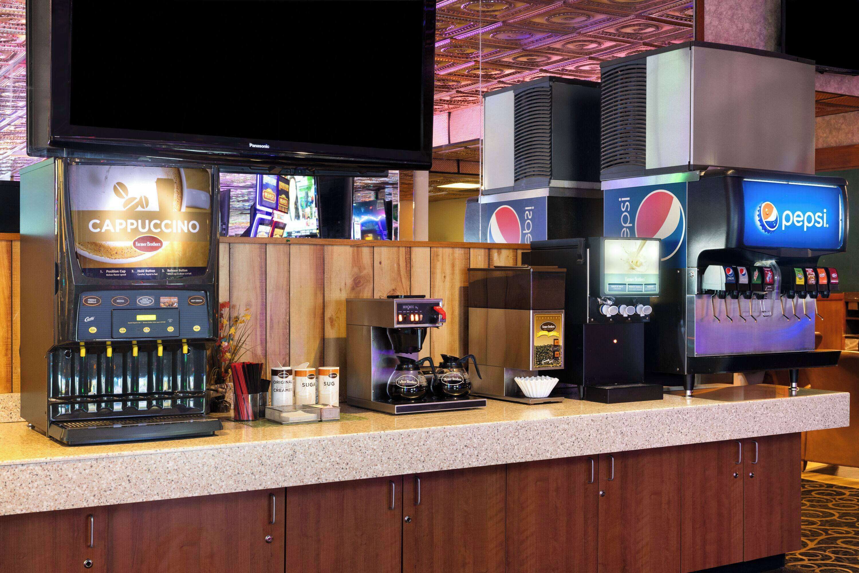 A coffee bar with a Cappuccino machine, a coffee maker, and a Pepsi dispenser.