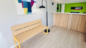 A room with a wooden bench, a floor lamp, a reception desk, and a colorful abstract painting on the wall. - Park Inn by Radisson, Quesnel (Quesnel)