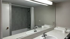 A modern bathroom with a large mirror, two sinks, and a shower area. - Park Inn by Radisson, Quesnel (Quesnel)
