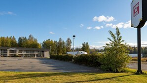 A motel with a large parking lot, a building with multiple rooms, and a sign indicating the motel name. - Park Inn by Radisson, Quesnel (Quesnel)