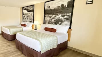Habitación de hotel con dos camas, una mesita de noche, una lámpara y dos cuadros en la pared.
