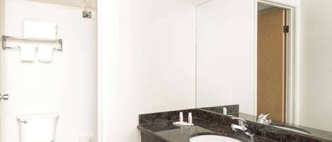 A modern bathroom with a white toilet, a sink with a large mirror, and a towel rack.