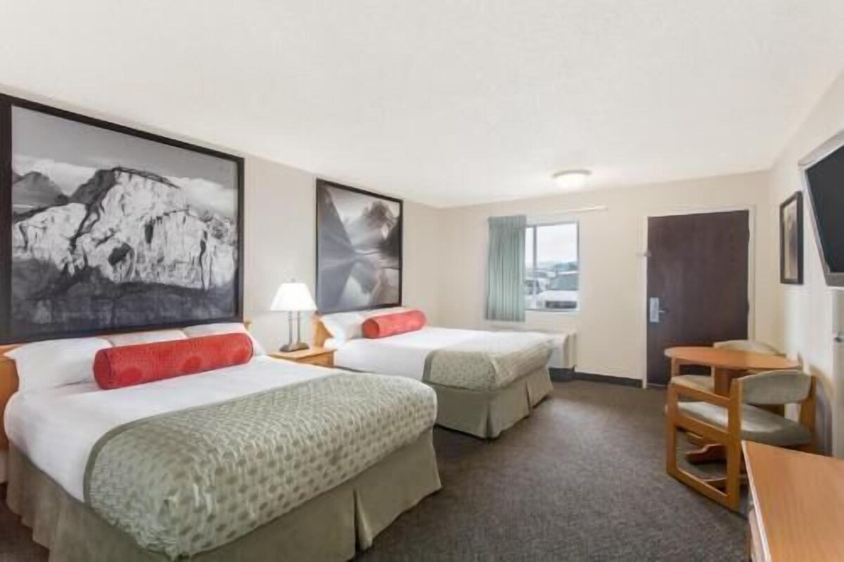 A hotel room with two beds, a desk, and a chair.